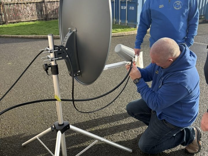 Setting up the portable satellite dish outdoors.